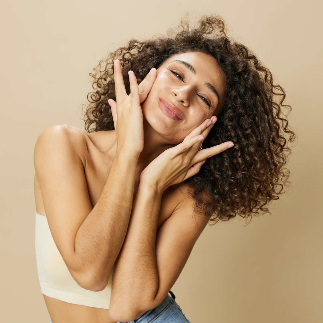 Woman with curly hair smiling and touching her face expressively