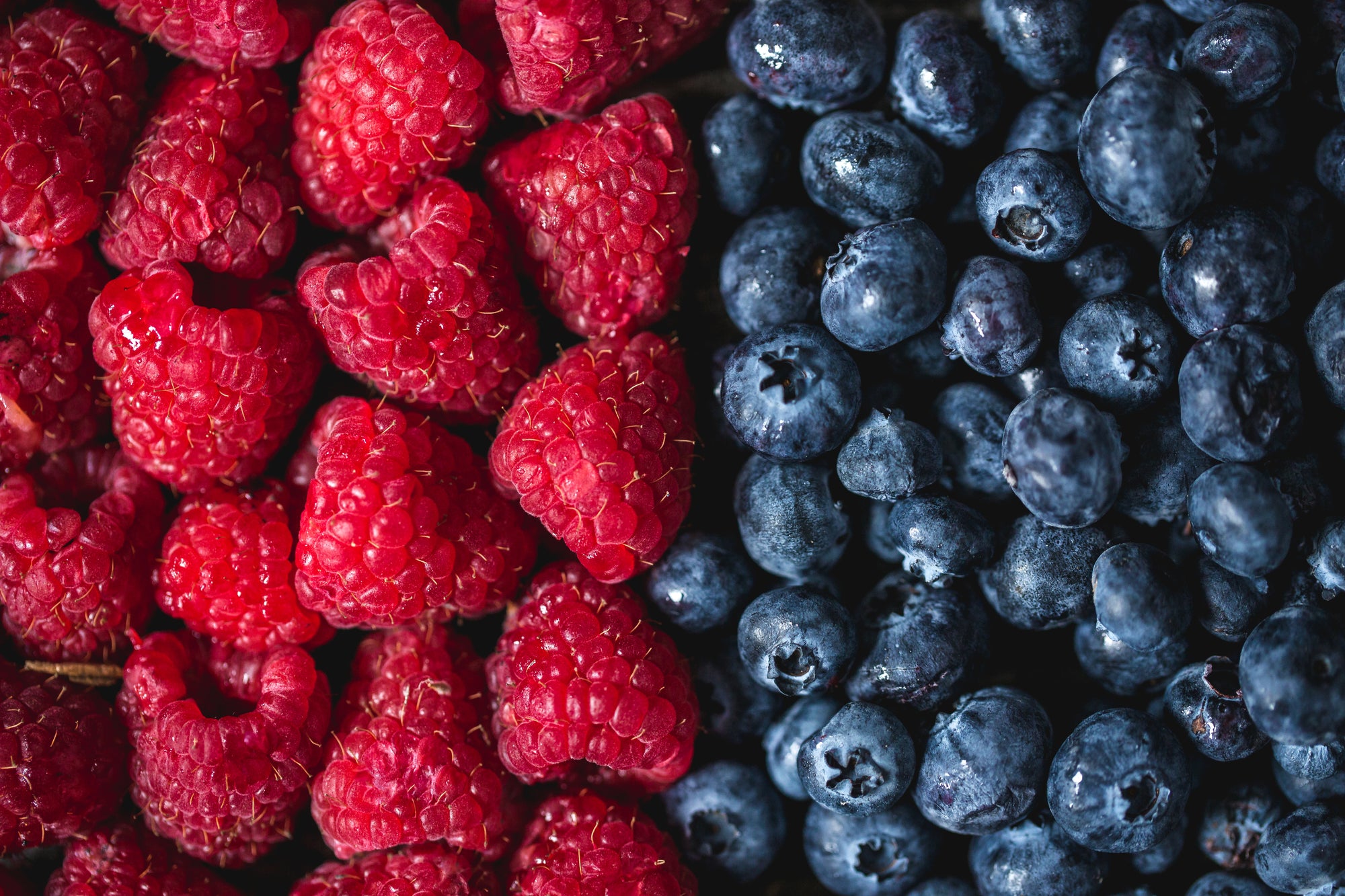 Fresh raspberries and blueberries side by side